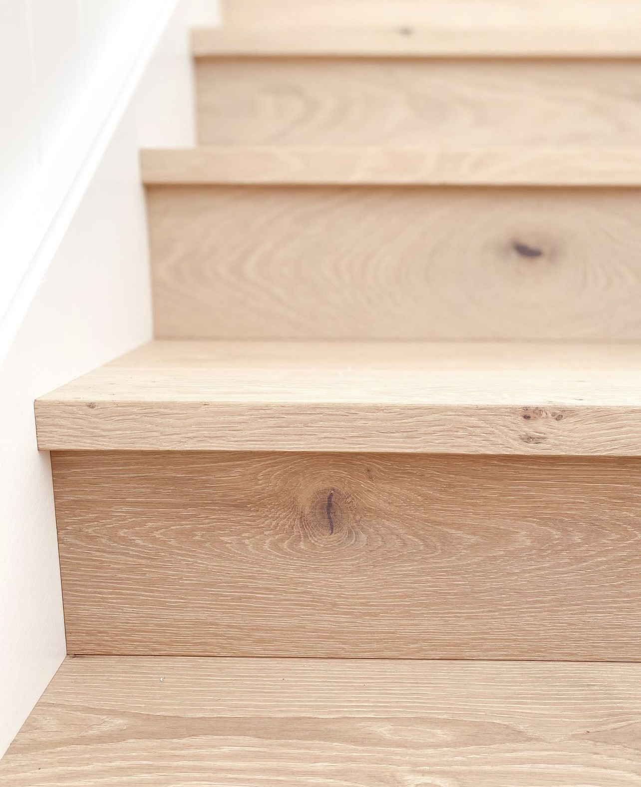 Close-up of a square stair nosing profile in light white oak showing the tread edge and riser joint in Tukwila, Washington.