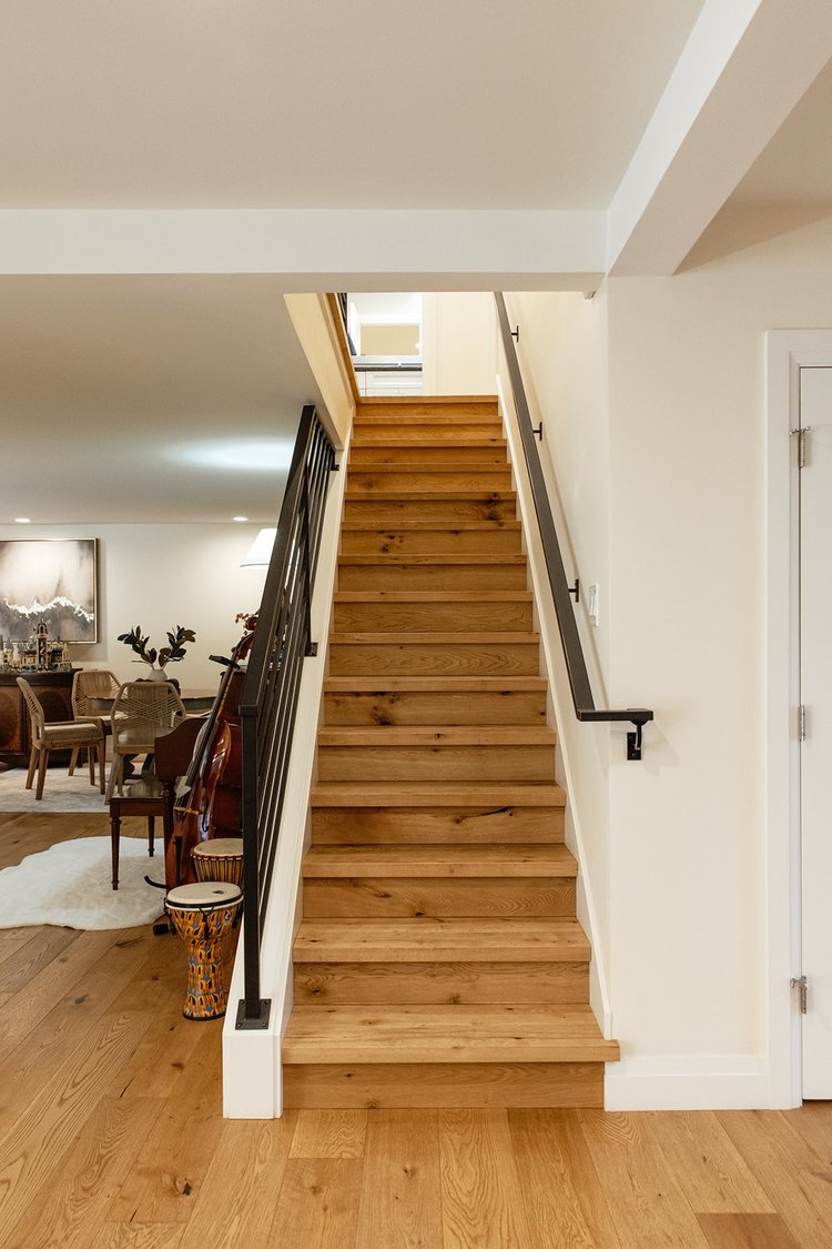 White oak stair nosings and matching risers on a straight staircase with a black metal handrail in Seattle, Washington.