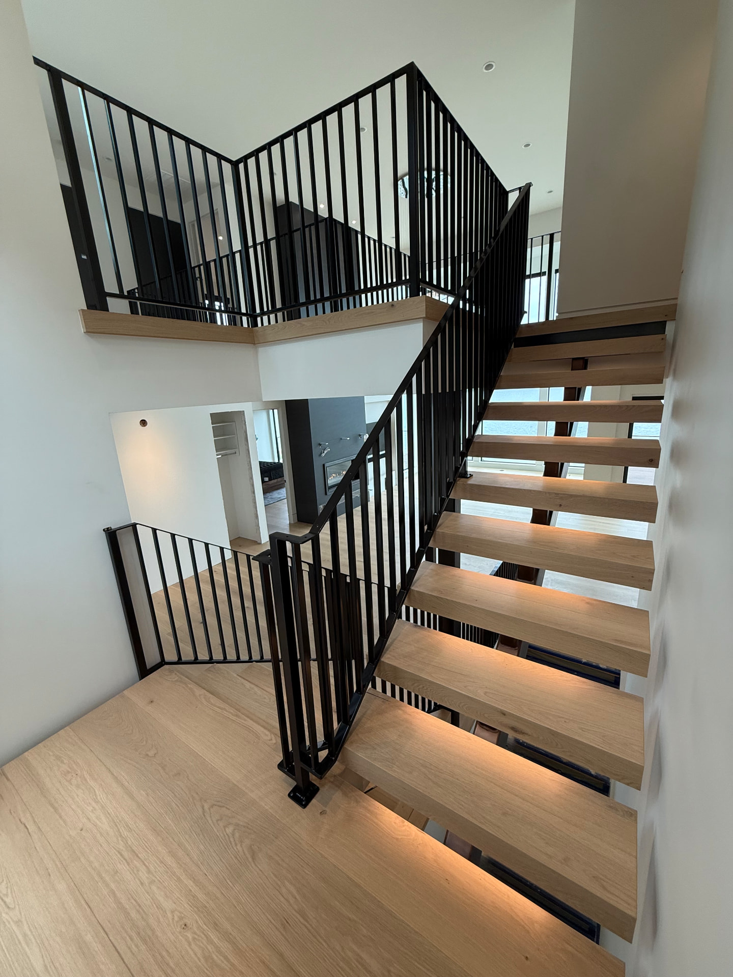 White oak floating block treads with under-tread LED lighting on a black steel mono-stringer staircase in Kirkland, Washington.