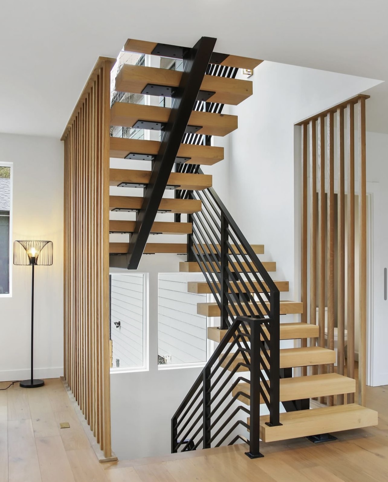 Floating white oak block treads with black steel stringer and wood slat screen wall in Seattle, Washington.