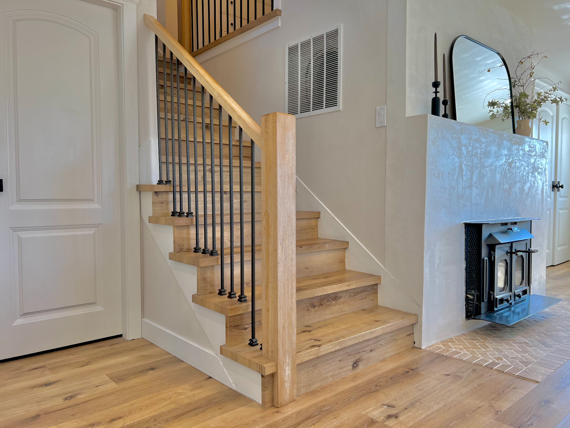 White oak return treads and risers on a winder staircase with iron balusters and a square newel post in Issaquah, Washington.