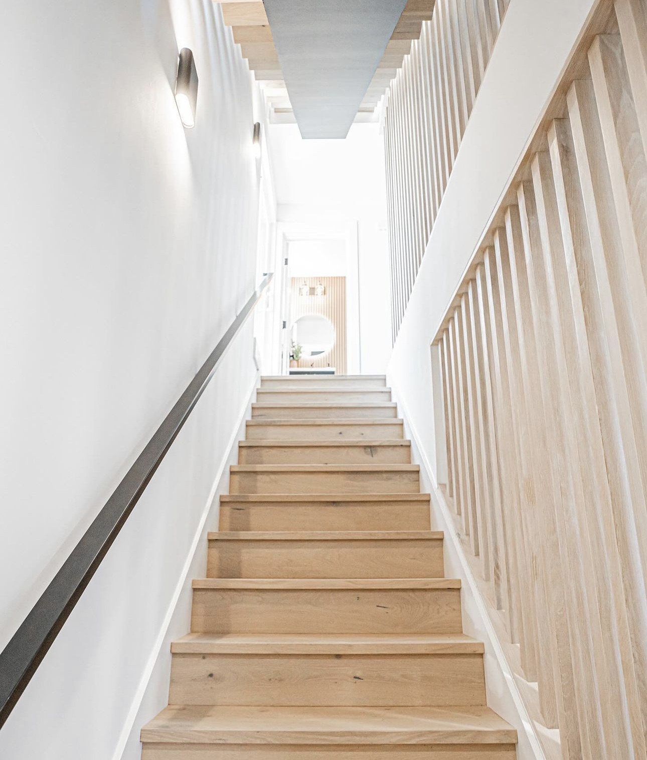White oak stair nosings and risers beside a vertical slat railing and slim black wall handrail in Everett, Washington.